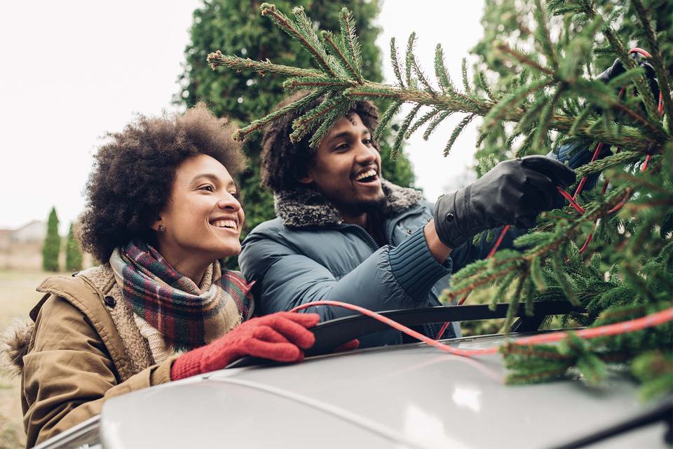 couple-tying-christmas-tree-to-roof-of-car.jpg