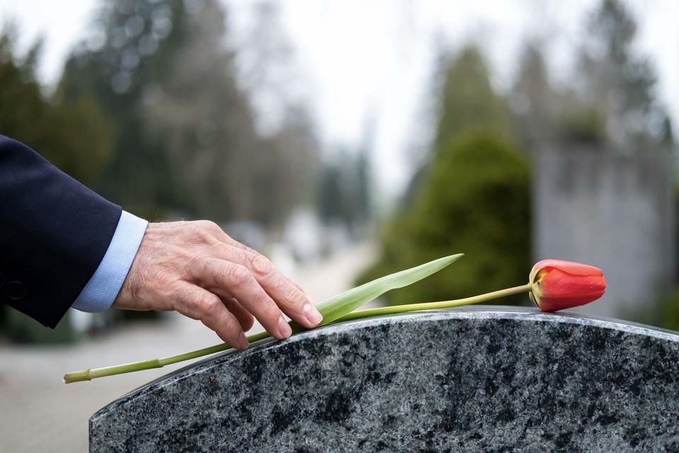 hand-placing-flower-on-headstone