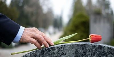 hand-placing-flower-on-headstone