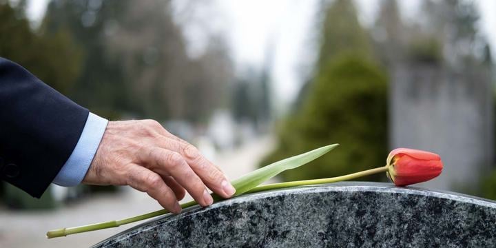 hand-placing-flower-on-headstone