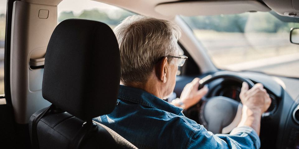 senior man with glasses driving