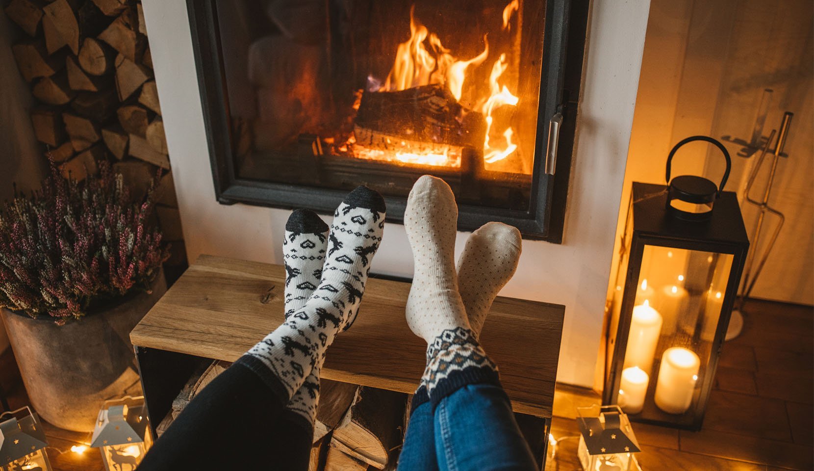 A couple warms their feet by the fireplace
