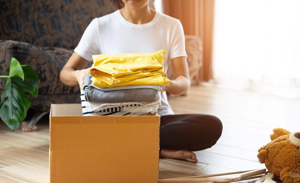 woman-placing-folded-clothes-in-cardboard-box.jpg